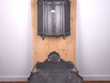 antique cast iron water fountain on wooden stand in a white walled room