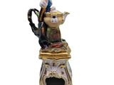 a figurine of a man sitting on top of a teapot