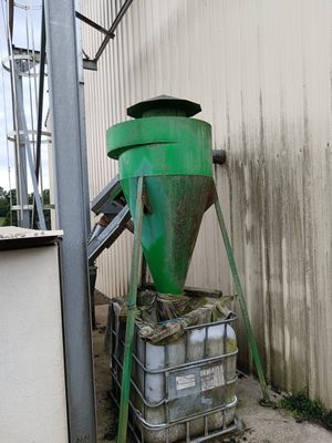 a green machine that is sitting next to a building