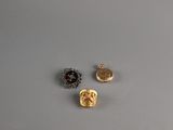 three gold and silver buttons on a gray surface