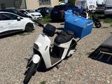 un scooter garé sur un parking, avec d'autres véhicules en arrière-plan