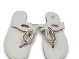une paire de sandales en cuir blanc ornées d'un nœud doré sur la pointe