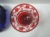 a red and white plate and a blue vase on a white table