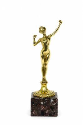 une statue en or représentant une femme tenant un verre à la main