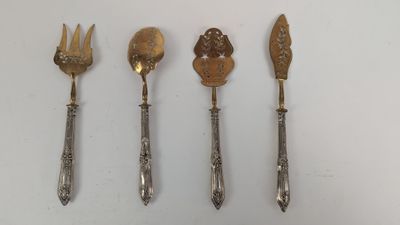 quatre cuillères et une fourchette sont alignées sur une surface blanche