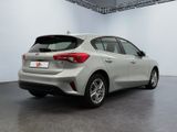 the rear end of a silver car in a white room