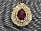 un gros plan d'un pendentif en pierre rouge et diamants posé sur un tissu noir