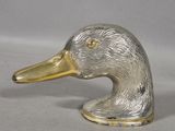 a silver and gold duck head on a white surface
