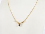 un collier en or orné de deux pierres bleues autour du cou d'un mannequin