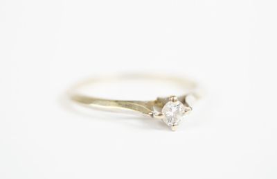 a close up of a white diamond ring on a white surface