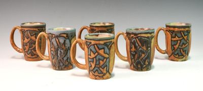 six mugs with designs on them are lined up in a row