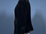 a black velvet jacket on a mannequin dummy against a blue background