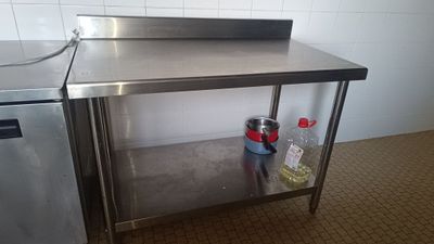 une table de travail en acier inoxydable équipée d'un évier et d'un lave-vaisselle