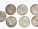 six different british coins are arranged in a circle on a white surface