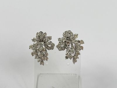 une photo d'une paire de boucles d'oreilles en diamant posées sur un socle transparent
