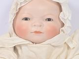 a baby doll that is wearing a white dress and bonnet