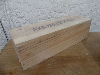 une boîte en bois posée sur une table, sur laquelle est accrochée une pancarte