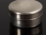 an image of a silver pill case on a black surface