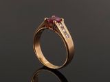 a close up of a gold ring with a ruby stone and diamonds