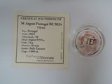 a small glass of wine next to a certificate on a table