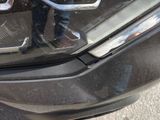 a close up of a car ' s headlight with a person standing next to it