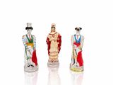 trois figurines représentant des personnes vêtues de costumes et coiffées de chapeaux, posées sur une surface blanche