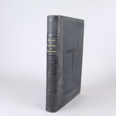 un vieux livre à la couverture noire posé sur une surface blanche