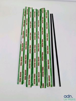 des pailles en papier vertes et blanches, accompagnées de baguettes, posées sur une table blanche