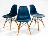 three blue plastic chairs with wooden legs against a white background