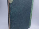 an old book with a green cover sitting on a white surface