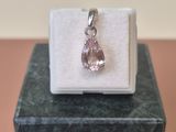 un gros plan d'un pendentif en diamant rose posé sur une boîte blanche