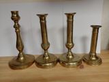 four brass candlesticks on a wooden table