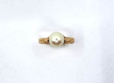 a close up of a pearl ring on a white surface