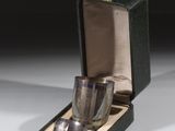 une tasse en argent et une cuillère en argent dans une boîte noire