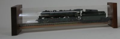 un train miniature dans une vitrine, posé sur un socle en bois