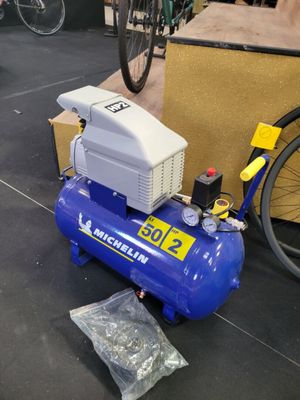 un compresseur d'air bleu posé par terre à côté d'un vélo