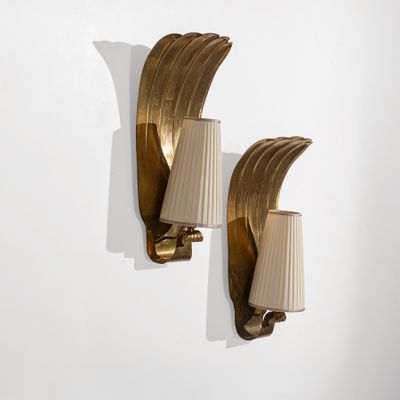 une paire d'appliques en laiton avec des lampes à abat-jour, fixées sur un mur blanc