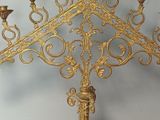 a gold colored candle holder on a stand with a clock on it