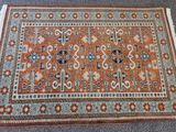 un tapis orange et bleu posé sur une moquette grise