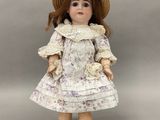 une poupée en porcelaine représentant une petite fille portant un chapeau et une robe