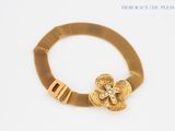 gold bracelet with a flower on a mesh bracelet with a clasp