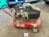 un petit compresseur d'air posé par terre dans un garage