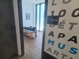 a hallway with a black door and a white wall with a sign on it