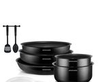 trois casseroles noires et une cuillère posées sur un plan de travail blanc