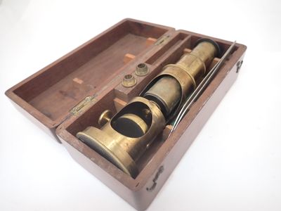 un vieux télescope en laiton dans un coffret en bois, posé sur une surface blanche