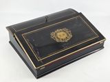 an antique black and gold box with a gold emblem on it