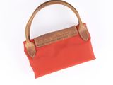 red and brown handbag with wooden handle on white background