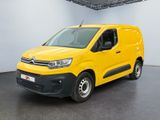 La camionnette jaune est garée dans une grande pièce au sol noir.