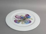une assiette blanche ornée de fleurs violettes, posée sur une table