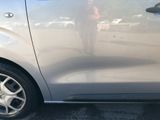 a silver car parked in a parking lot with a person taking a picture